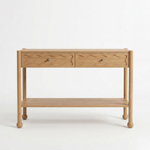Front view of Arlo natural oak console table with two wave-carved drawers, open shelf, and bun feet