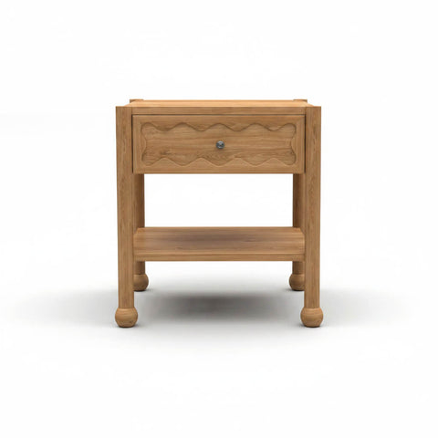 Front view of Arlo solid natural oak side table with hand-carved wave drawer front, open shelf, and bun feet