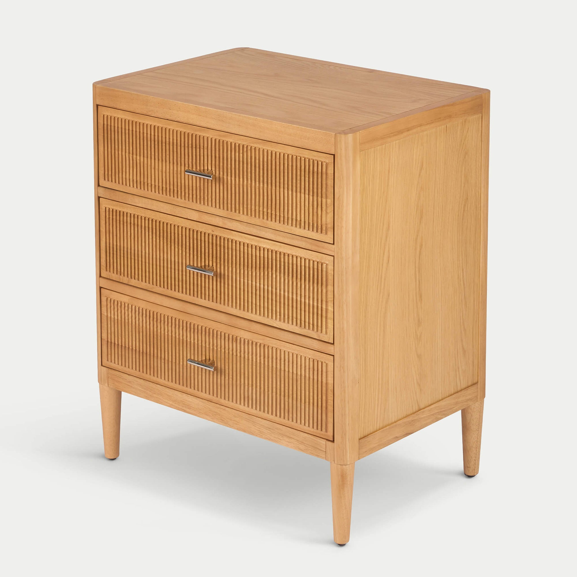 Three-quarter view of Arlo wide chest in natural oak showing fluted drawer fronts and solid wood legs