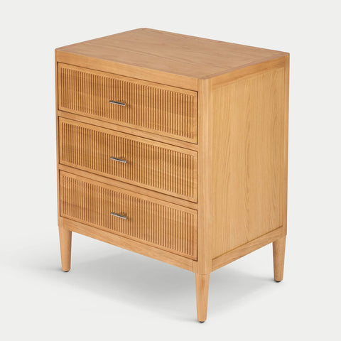 Three-quarter view of Arlo wide chest in natural oak showing fluted drawer fronts and solid wood legs