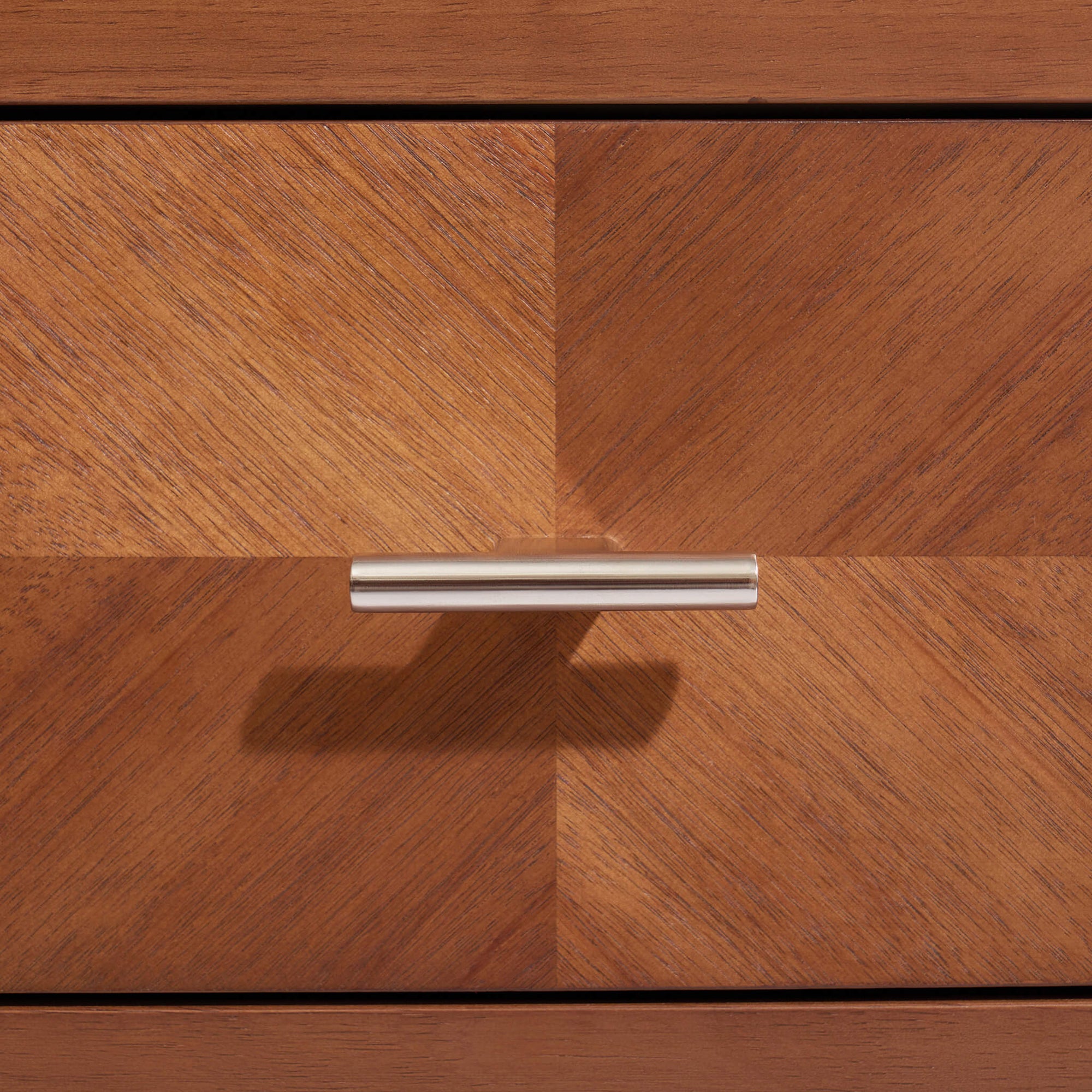Close-up of the Krevon Wings solid wood nightstand drawer in a dark walnut finish, featuring a decorative chevron wood grain pattern and a sleek stainless steel cylinder handle.