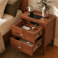 Solid wood 2-drawer nightstand in walnut finish with built-in charging station, drawers open showing phone charging and storage compartments, tablet and vase on top
